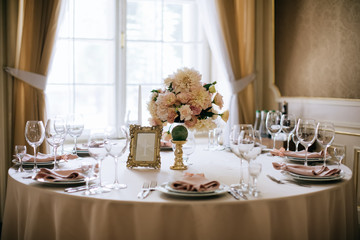 Elegant wedding table set with plates, glasses, cutlery, candles and flowers
