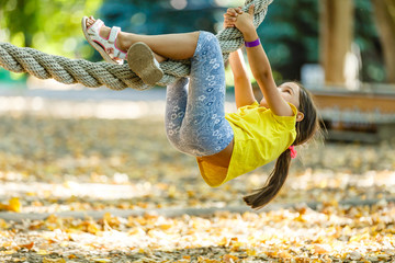 Charming little girl climbs on rope