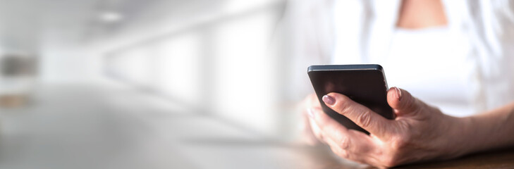 Woman's hands using a mobile phone; panoramic banner