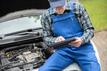 Mechanic using digital tablet for checking car engine