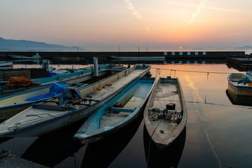 オレンジ色の日の出と琵琶湖と漁船と飛行機雲