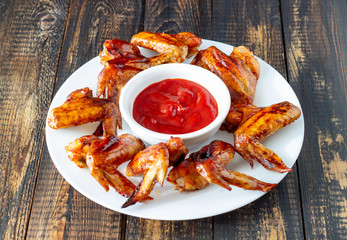 Grilled chicken wings and red sauce on a wooden background. Snack to beer. Barbecue. 