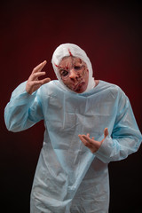 Crazy zombie horror make up. Person in blue madical shirt and bandaged head. Scars, deep scratches...