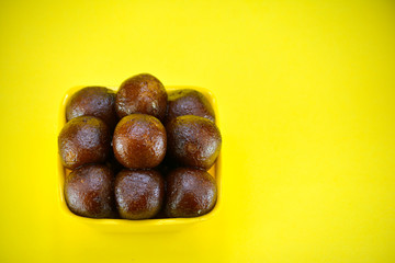 Indian dessert gulab jamun served in yellow bowl