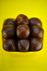 Indian dessert gulab jamun served in yellow bowl