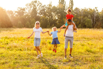 Fototapeta premium Young happy family with two children in the summer park