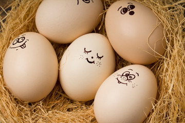 Eggs with funny faces in straw nest . close up