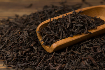 Scattered leaves of black tea on a wooden table.