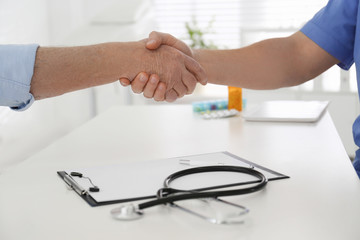 Fototapeta na wymiar Doctor and senior patient shaking hands in office , closeup
