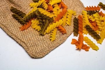 Composition of raw pasta uncooked tricolore fusilli, pasta twist shape. Close up and selective...