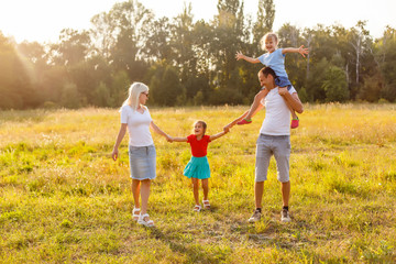 Fototapeta premium Młoda szczęśliwa rodzina z dwójką dzieci w parku latem