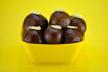 Indian dessert gulab jamun served in yellow bowl