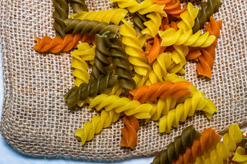Composition of raw pasta uncooked tricolore fusilli, pasta twist shape. Close up and selective...