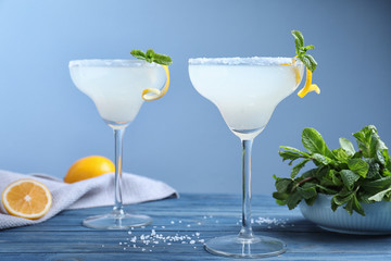 Glasses of tasty Margarita cocktail on blue wooden table