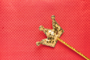 golden magic stick from sequins in crown shape on red background. Creative flat lay in minimal style. Copy space for text