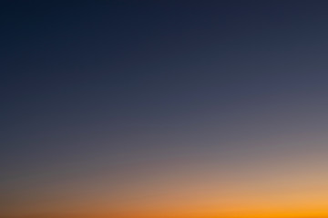 Heaven at early morning with copy space. Smooth orange blue gradient of dawn sky.Sunset, sunrise backdrop.Predawn clear sky with orange horizon and blue atmosphere.  Background of beginning of day.