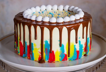bright birthday cake with chocolate on a light background with balloons