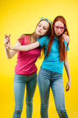 lifestyle people concept: two pretty young school teenage girls having fun happy smiling on yellow background wearing glasses