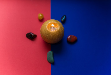 Mysterious candle on a colorful background with a stones 
