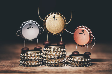 Crown cork or bottle cap miniature figures on a medalist award ceremony, concept beverage winner