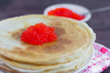 Freshly baked pancakes with red caviar on a plate. Traditional home-made pastries. Pancake day