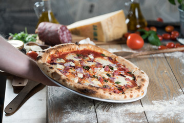 Pizza with meat, basil and cheese on plate