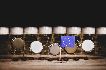 Crown cork miniature figures and beer glasses in the back, european flag, concept country beer...