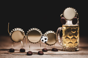 Crown cork or bottle caps miniature figures with a soccer football and a beer glass, concept...