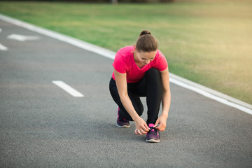 beautiful young woman runs in summer park on a treadmill