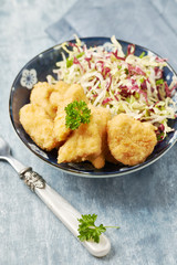Chicken nuggets with raw salad on bright wooden background. 