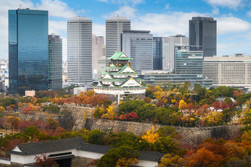 Fototapeta premium Zamek Osaka z ogrodem japońskim i wieżowcem biurowca miejskiego jesienią w Osace w Japonii. Turystyka w Japonii, budowanie historii lub koncepcja kultury tradycji i podróży