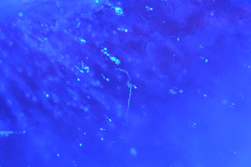 Abstract background of illuminated blue ice texture with air bubbles inside