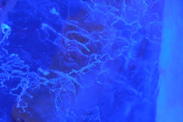 Abstract background of illuminated blue ice texture with cracks and bubbles inside