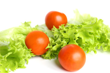 Red cherry tomatoes and lettuce leaves on white background