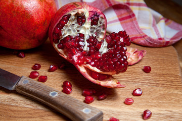 Fresh red pomegranate with vintage knife on a wooden background..