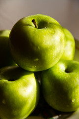 Five green apples piled up in the sun