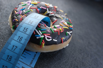 Close up of measurement tape and donut on table 