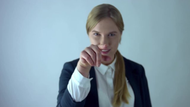 Fancy business girl pointing with finger toward camera in studio with white background