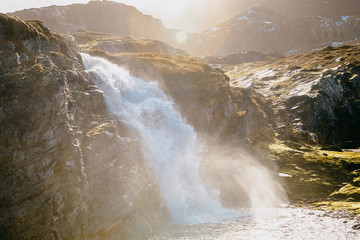 Powerfull Waterfall in rugged and rocky landscape with direct sunlight