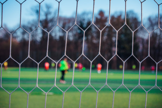 Football match behind soccer net, sport photo
