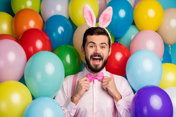 Photo of funny cool guy colorful decorations easter party festive party mood wear pink shirt bow tie suspenders fluffy bunny ears on balloons creative design background
