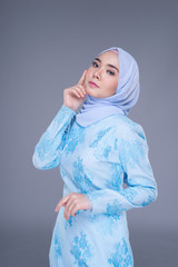 Beautiful Muslim female model wearing pastel blue modern kurung with hijab, a urban lifestyle apparel for Muslim women isolated on grey background. Beauty and hijab fashion concept. Half length