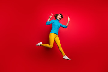 Fototapeta na wymiar Full size photo of cheerful candid girl jump enjoy autumn spring weekends make v-sign swear good look blue clothing isolated over bright color background