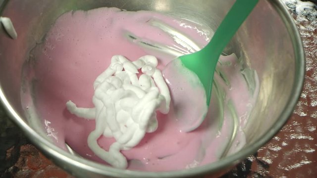 Putting shaving cream along with glue and food color mixture to make slime