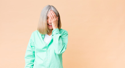 middle age cool woman laughing and slapping forehead like saying d’oh! I forgot or that was a...