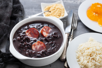 typical brazilian food black beans with smoked sausages in white bowl