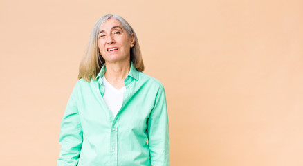 middle age cool woman looking happy and friendly, smiling and winking an eye at you with a positive...