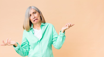 middle age cool woman shrugging with a dumb, crazy, confused, puzzled expression, feeling annoyed...