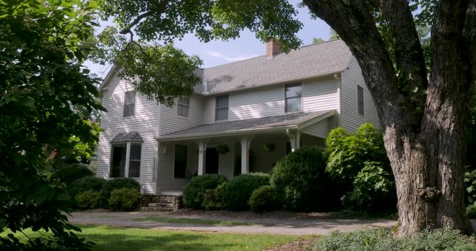 Establishing shot of an old two story historic southern home in the summer