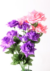 Artificial violet and pink roses on white background